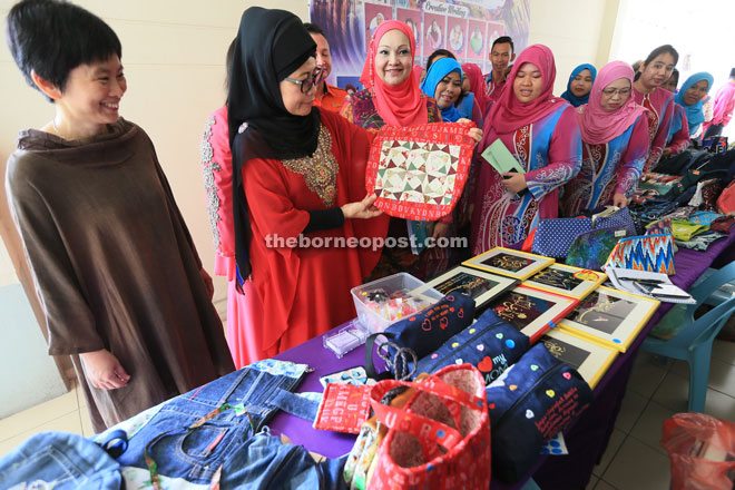 Fatimah (second left) looks at a handmade bag on display at the event. Also seen are Chye (left) and Women and Family Department director Noriah Ahmad.