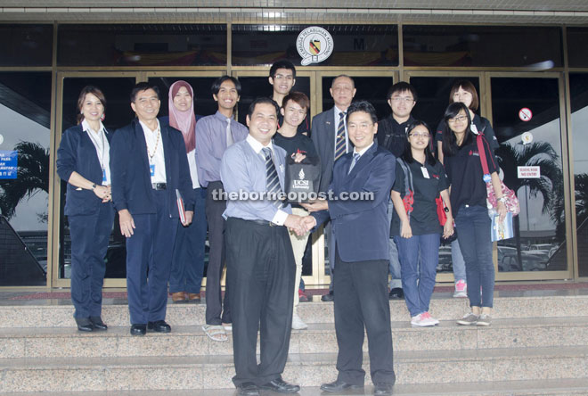 Bernard (left) presents a souvenir to Lau at the end of the visit while the students look on.