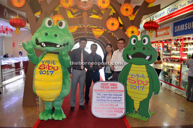 Wong (left) and others giving the thumbs-up to the mascot-naming competition promotional placards at the main entrance of Wisma Sanyan.