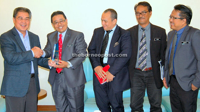 Siringan (left) receiving a memento from Kamal while the other JTK senior officials look on. 