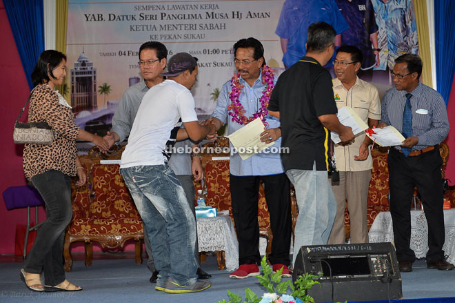 Musa presenting a land title to one of the villagers in Sukau while its assemblyman, Datuk Saddi Abdul Rahman looks on. Also seen here are Kinabatangan district officer Yassin Nasir (right) and Land and Survey Department director Haji Safar Untong (second right).