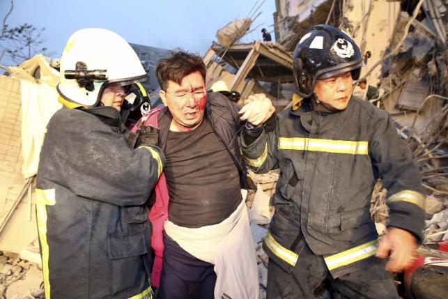 Rescue personnel help a victim at a damaged building after an earthquake in Tainan, southern Taiwan, February 6, 2016. REUTERS/Stringer