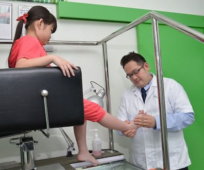 Dr Lee examines the foot of a child.