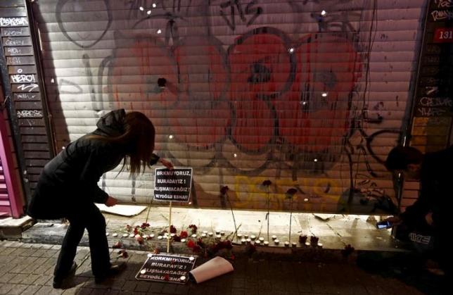 A woman places carnations and a sign at the scene of a suicide bombing at Istiklal street, a major shopping and tourist district, in central Istanbul, Turkey March 19, 2016. The signs read, "We are not afraid, we are here! We will not get used to it! Beyoglu district shopkeepers". REUTERS/Murad Sezer