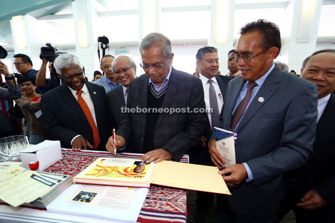 Len (second right) watching Adenan sign the guestbook at one of the exhibition booths at SCaT. Also seen are Jabu (fifth right), Morshidi (third right) and Nansian (right). — Photos by Muhammad Rais Sanusi