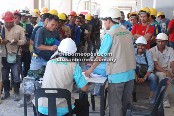 PERIKSA: Pegawai CIDB memeriksa dokumen pekerja binaan semasa operasi di tapak pembinaan di Kolombong, kelmarin.