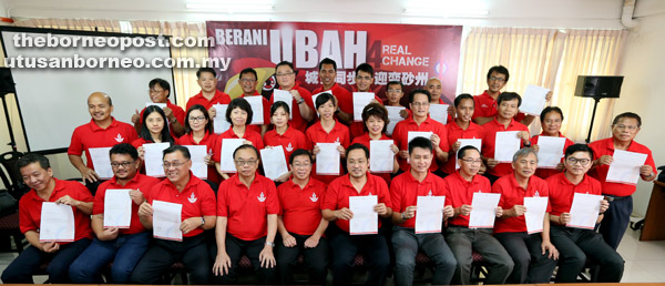 TAWAN SARAWAK: Chong (duduk, lima kanan) bersama calon-calon DAP lain menunjukkan watikah lantikan parti untuk bertanding dalam PRN11.