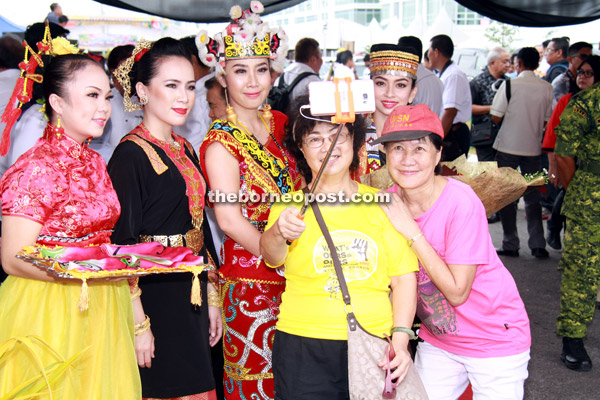 Visitors take an opportunity to take a wefie with ladies in traditional costumes.  
