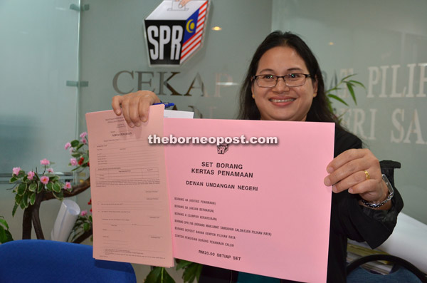 An EC personnel holds a sample of the nomination papers. The forms will be available until Sunday evening, at RM20 per set.
