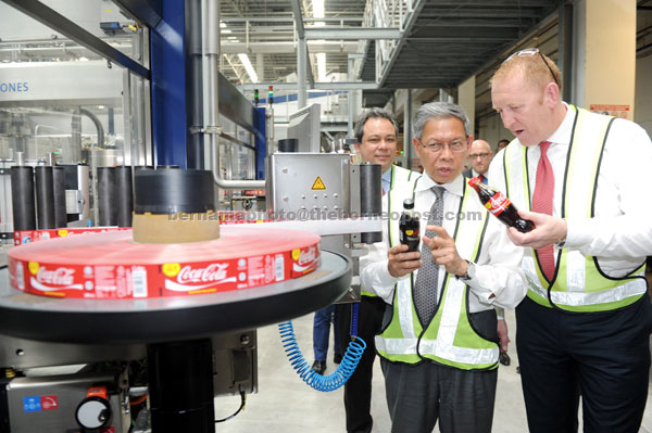 Mustapa listening attentively as CEO of Coca-Cola Bottling Investment Group (Singapore-Malaysia-Brunei) Stephen Luskin briefs him on the Coca-Cola just out of production line.— Bernama photo