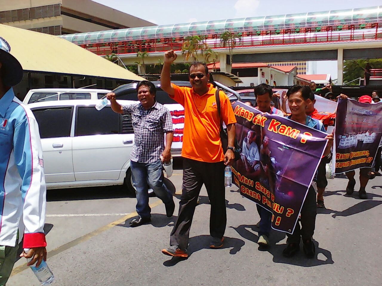 S. Manikavasagam (orange shirt) leading the group walking through the police station compound shouting "We want IC"