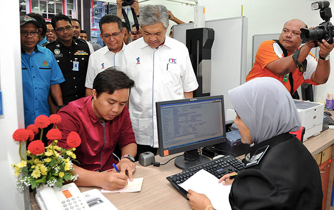 Zahid observes Muhammad Zulkifli Abdullah renewing his passport at the Immigration counter at  Terengganu RTC. — Bernama photo