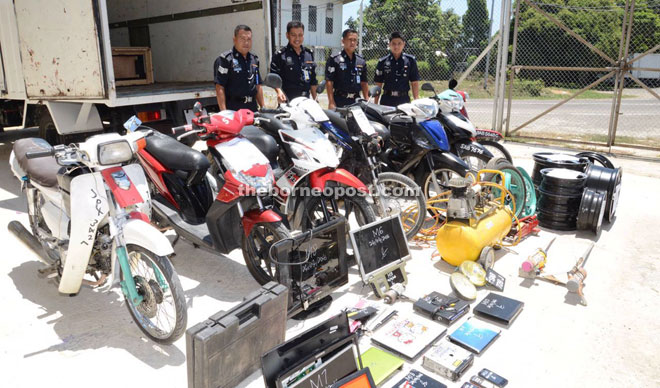 George (third right) and other police officers with the motorcycles, sport rims and other stolen items recovered from the suspects.