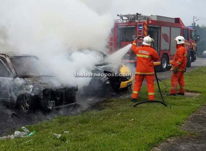 Firemen extinguishing the flames of a Perodua Myvi (two cars were burnt) on fire at Taman Suria Jaya in Matang.