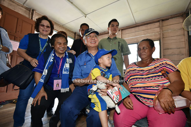 Najib carrying a boy at the clinic in Siburan during his walkabout. He is accompanied by Dr Jerip (on his right).