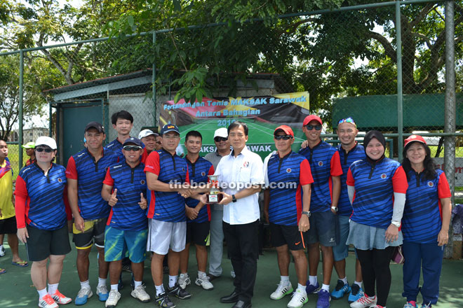 Hii (sixth right) hands over the championship trophy to Kuching Maksak team.
