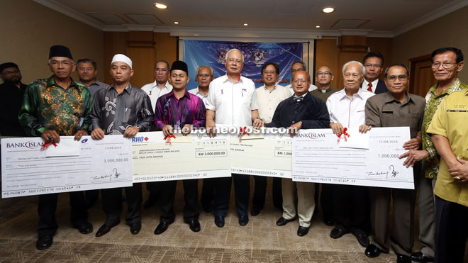 Najib (front row, fourth left) posing with the recipients of the cheques and other ministers after the cheque presentation ceremony at the KIA VVIP terminal yesterday. — Photo by Muhammad Rais Sanusi