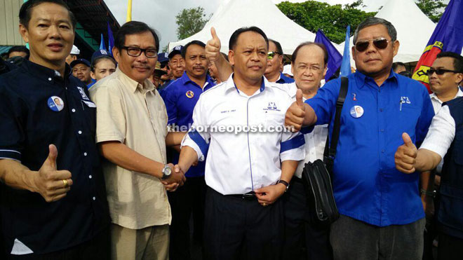 Henry (centre) shakes hands with Boniface before he and the BN team made their way to the nomination centre on Monday. 