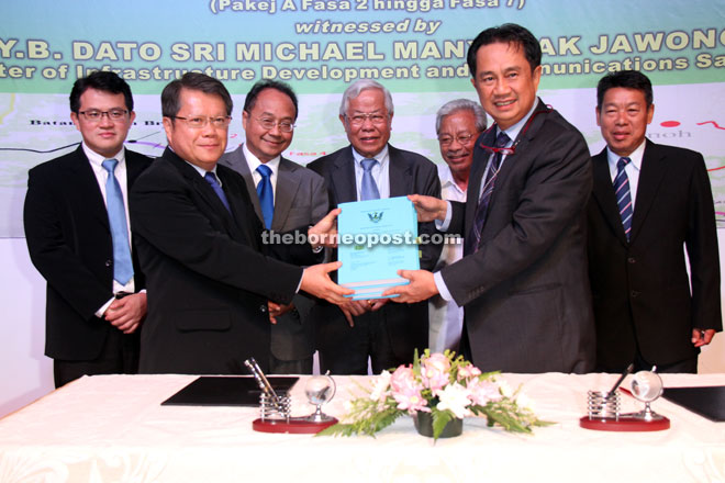 Zuraimi (right) exchanging documents with a representative from one of the contractors after the contract signing as Manyin (centre) looks on. Also seen are (from right) Belayong, Masing and Wilson.