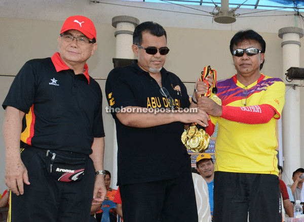 Hasbi (centre) presents a prize to SK Melayu Pusat headmaster Usop Sapihi.