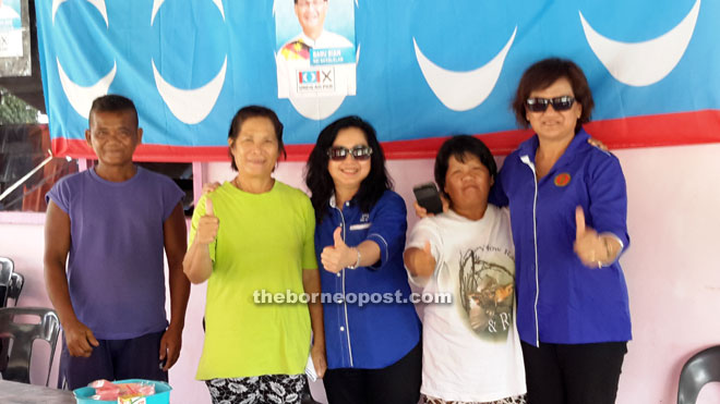 Chiew (centre) gives the thumbs-up during a photocall with supporters in Limpaki, Merapok. At right is Hellen.