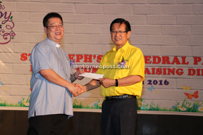 Lee (right) presents a RM100,000-cheque to Bishop Richard.