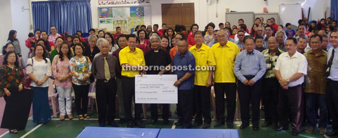 Lee (front, second left) presents the mock cheque for RM50,000 to Rev Fr Donald on his left and Moses (seventh right).