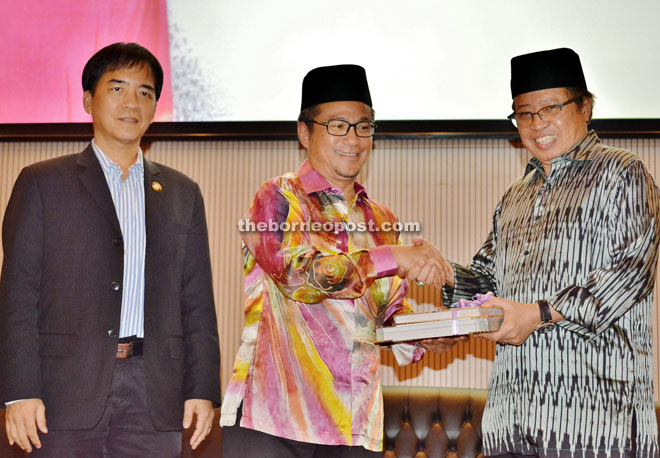 Dr Annuar (center) handing over a souvenir to Abang Johari while Hii looks on.