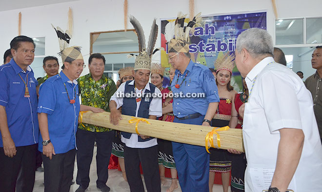 Hassan presenting a rattan mat to Najib, witnessed by (from left) Majang and Rundi.