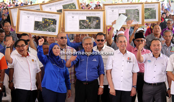 Adenan (centre), together with (from left) Sajeli, Jamilah Anu and Wan Junaidi (second right) have their pictures taken with the crowd and NCR land title recipients after presentation ceremony. — Photos by Chimon Upon