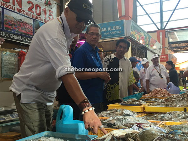 Nazri (left) looks at the fresh seafood on sale at Medan Niaga Satok. On his left is Fadilah.