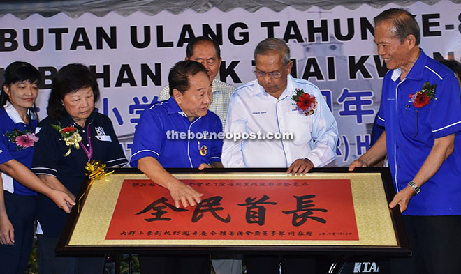 Adenan (second right) accepts a specially framed calligraphy painting from Tiong (right), as Wong (third left) explains the meaning of the Chinese characters. Looking on at second left is Lau.