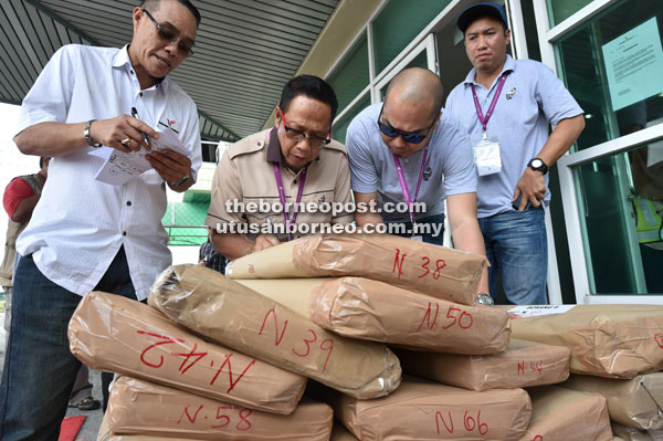 TELITI: Takun (dua kiri) dibantu para pegawai SPR Sarawak memeriksa peralatan pilihan raya yang akan dihantar ke 41 kawasan DUN seluruh negeri, semalam.