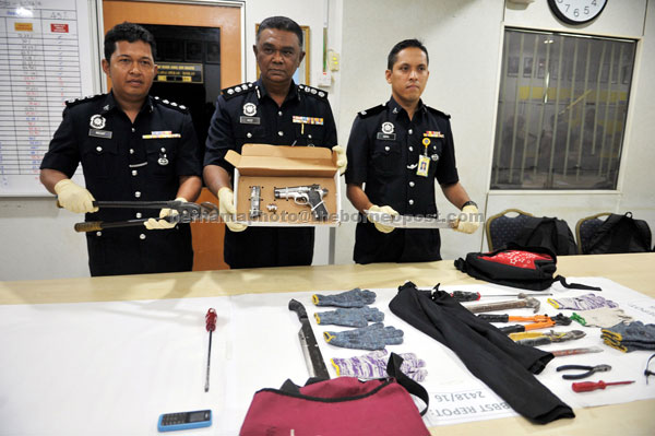 Abd Aziz Ali (centre) and his officers showing a Smith & Wesson 9mm automatic pistol and other items seized from house break-in suspects during the press conference. — Bernama photo