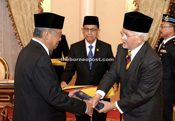 Taib (right) hands over the Instrument of Appointment to Adenan in Kuching last night. 
