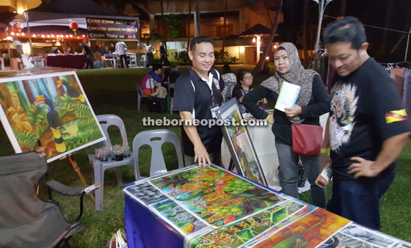 Local batik painter Noel Beluluk (left) entertaining customers at his stall.