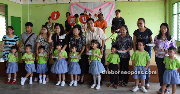 Lau (centre) receives a gift from the children. Teresa is seen at fourth left. At fourth right is a director of the management board Wong Ee Sing.