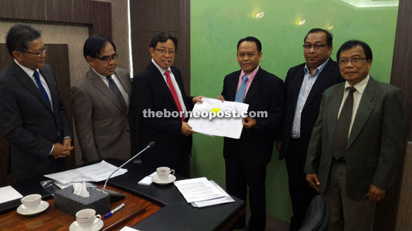 Henry (third right) and Abang Johari (third left) together hold the Bau master plan, as others look on.