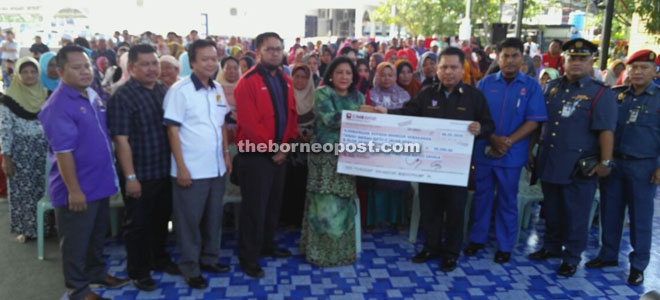  Alijus (right) receiving a mock cheque of RM49,200 contributions from SESB general manager (Corporate Services) Wan Maria Othman Lee as aid for the Mile 2 Apas fire victims. 