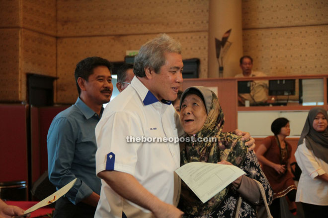 A lady recipient shows her gratitude to Awang Tengah after he presented her with the land title.