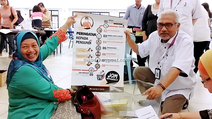 Hashim (right) with an officer hold up a poster during the visit.