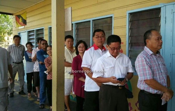 DAP candidate for Tanjong Batu Chiew Chiu Sing (third right) queues to cast his vote at SK St Anthony. The Tg Batu incumbent arrives with his wife at 9am.