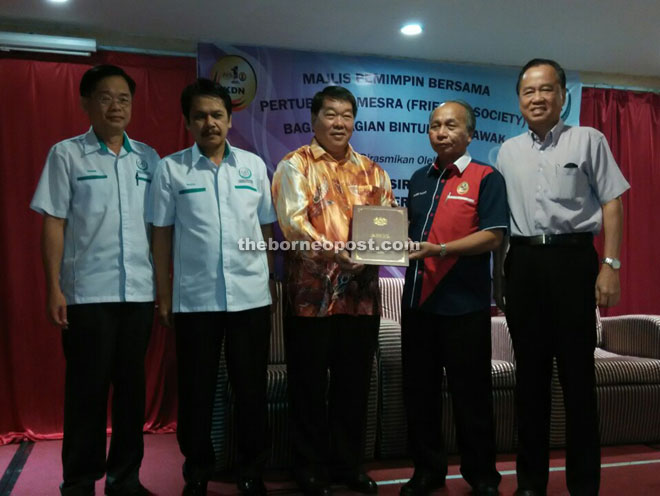 Masir (second right) presents a certificate of recognition to the representative of one of the oldest NGOs in Bintulu as Razin (second left) and others look on.