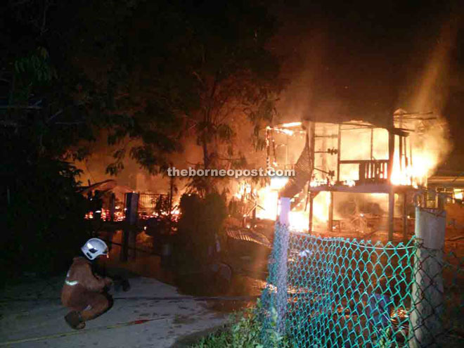 Fire fighters putting out the fire that destroyed the house at Kampung Contoh in Petagas on Thursday.