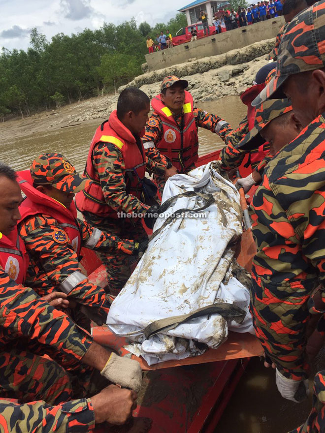 Bomba personnel carry the body to the ferry point in Sebuyau.