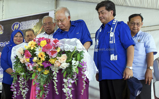 Najib signs a plaque to commemorate the opening of SK Pusa as Mahdzir (third left), Rohani (left) and Razaili (right) look on. — Bernama photo (File Photo)