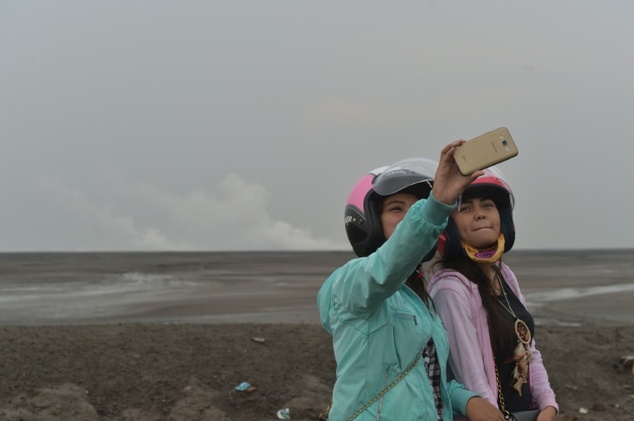 Indonesian tourists take selfies in Sidoarjo, East Java, where a mud volcano erupted in May 2006 swallowing entire villages. Photo by AFP