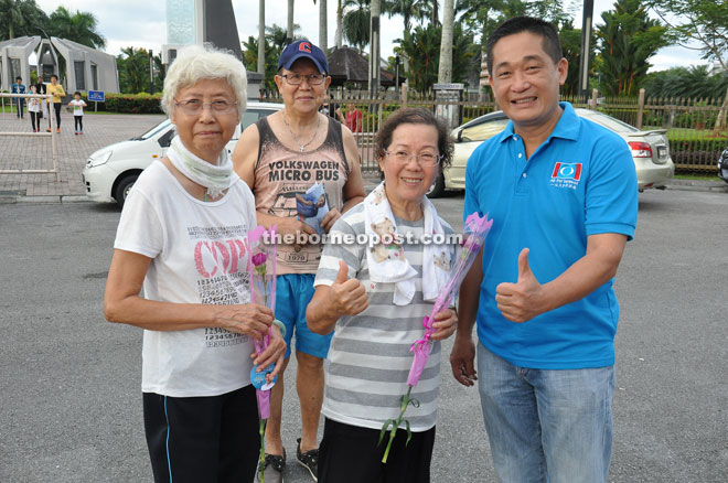 See (right) gives the thumbs-up to mothers after presenting them with carnations to commemorate Mother’s Day. 