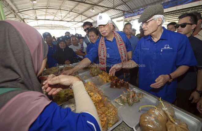 Najib visiting the Medan Niaga Saratok during his walkabout.  At right is Wahab Aziz while Kilat is seen standing behind the prime minister. — Bernama photo. 