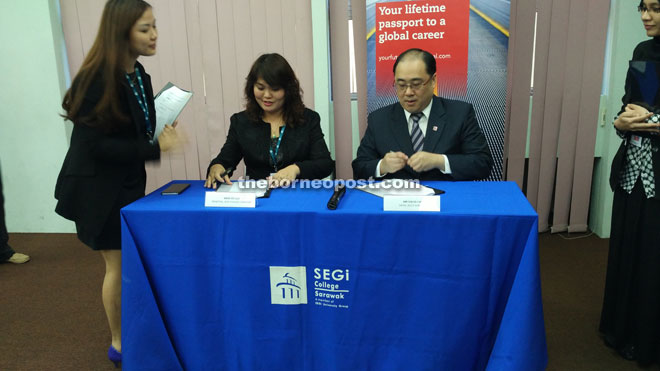 Lau (seated left) and Chin sign the Memorandum of Agreement. 